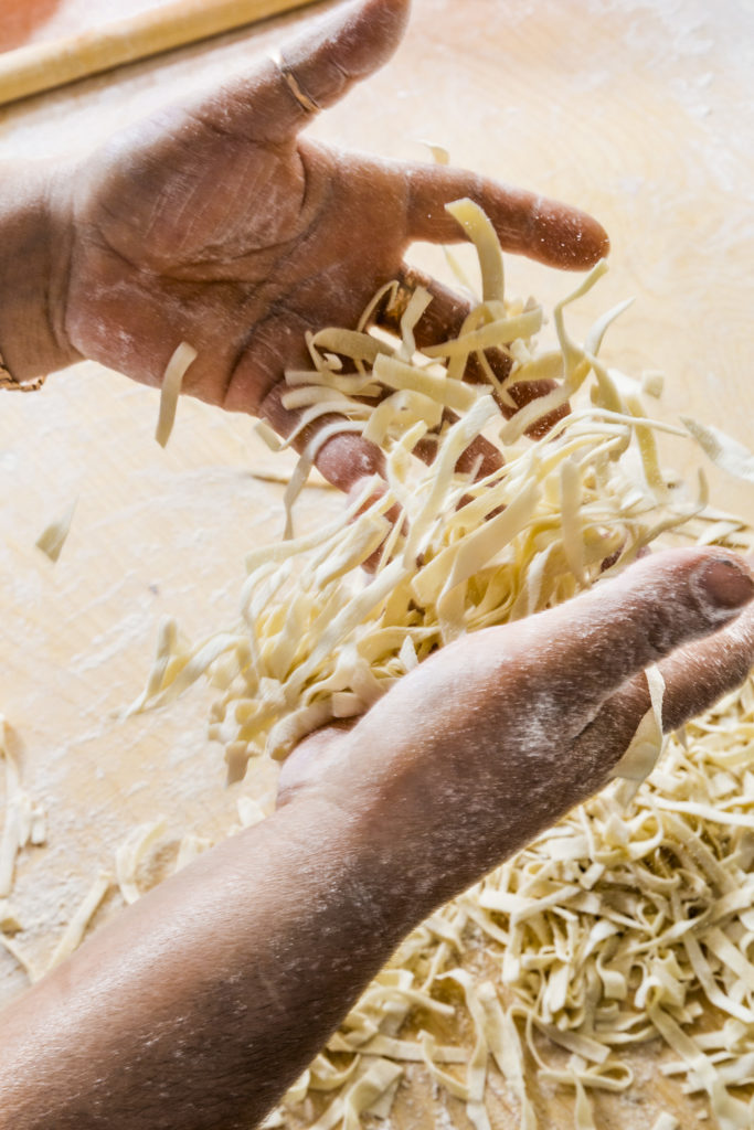 Fresh pasta runs through hands 