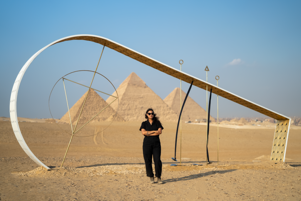 A woman standing in front of a sculpture and the pyramids