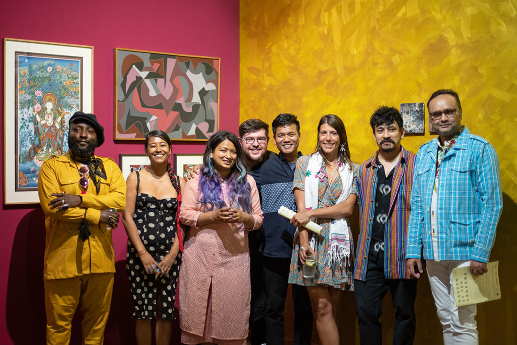a group of people standing in front of a pink and gold wall