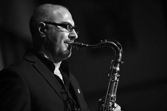 A bald man playing the saxophone
