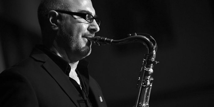 A bald man playing the saxophone