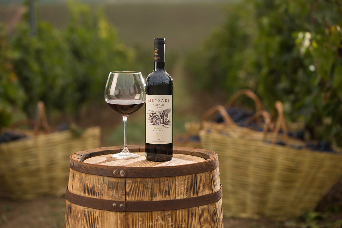 A glass of red wine and a bottle on a barrel 