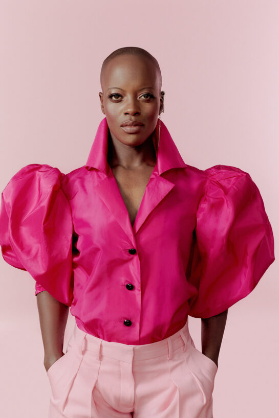 A woman wearing a puffer sleeve hot pink shirt and light pink trousers