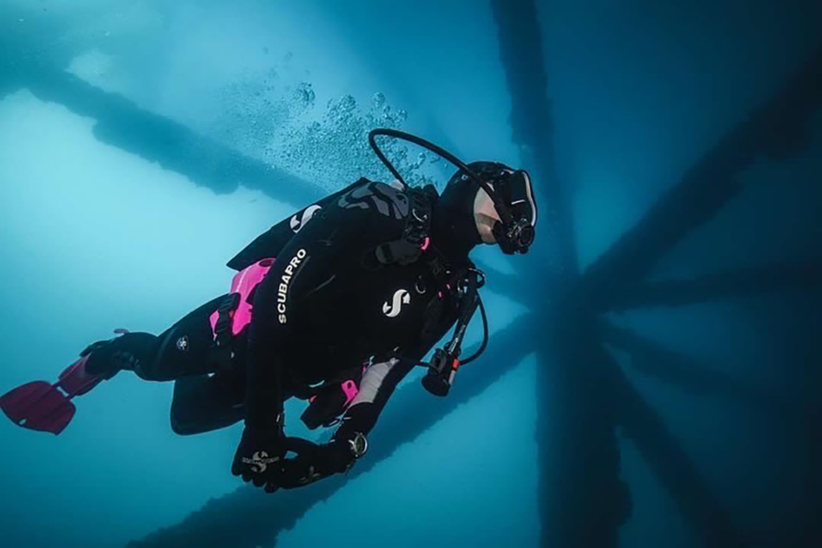 scuba diver in the blue ocean swimming near oil rig