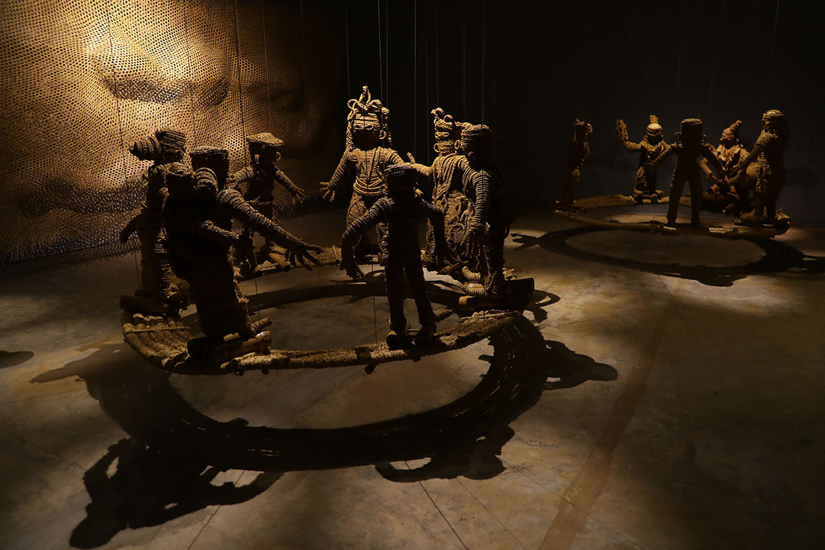 sculpture of figures standing in a circle in a dark room